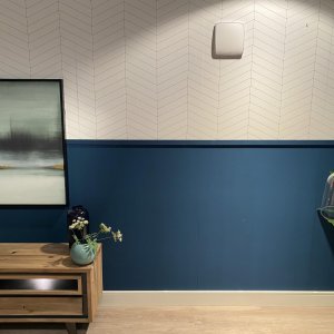 Woonkamer met CAREBRICK WTW-unit hoog aan de wand en verwarmde plint langs de vloer; voorbeeldopstelling van het Anti-Condensatie Systeem.