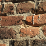 Close-up van een bakstenen muur met verweerd/slecht voegwerk, mogelijke oorzaak van doorslaand vocht.
