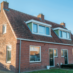 Bakstenen woning met spouwmuur; illustratie bij uitleg over vochtproblemen in de spouw.