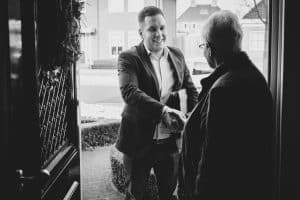 Vochtexpert van Carebrick schudt de hand van een bewoner bij de start van een huisbezoek/vochtinspectie.