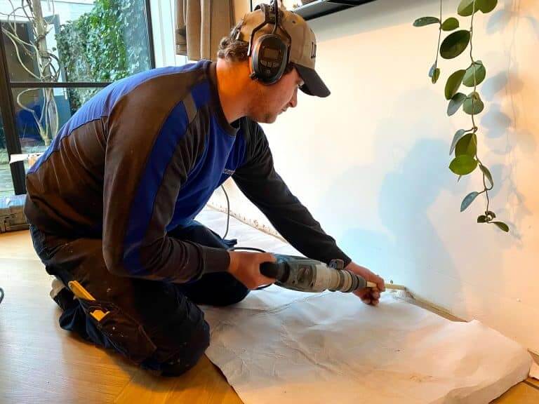 Carebrick-medewerker boort laag in een binnenmuur voor een injectiebehandeling