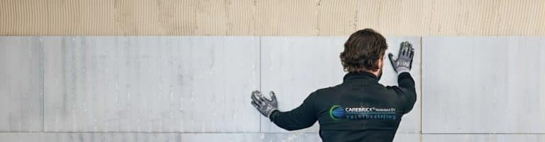 Een medewerker plaatst minerale binnenwandplaten tegen een voorbereide wand