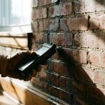 Professionele vochtmeter meet waterschade op verweerde bakstenen muur met opstijgend vocht en condensatie