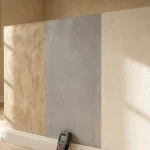 Gerenoveerde muur met drie vochtbestendige afwerkingsmaterialen, waterdruppels parelen af, vochtmeter aan de basis