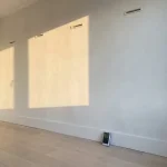 Witte gedroogde muur met vochtmeter die nul aangeeft in modern Nederlands interieur met natuurlijk licht
