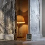 Doorsnede van binnenmuur met watervlekken en vochtdruppels naast condensatie en rijppatronen, digitale thermometer en vochtmeter aan de basis
